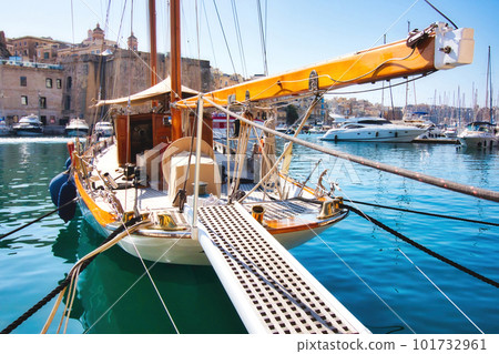 A luxury sailboat moored in a Mediterranean harbor with the gangplank extended 101732961