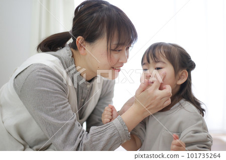 Parent and child applying moisturizing cream 101735264