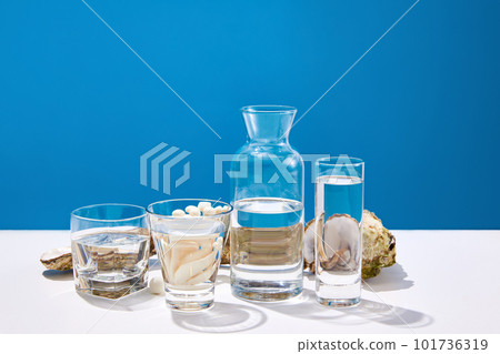 Still life with seafood, oysters and glasses with water on white table over blue studio background. Sea, ocean harvest. Chic menu 101736319
