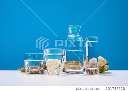 Still life with seafood and glasses with water on white table over blue studio background. Sea, ocean harvest. Fresh oysters reflections 101736320