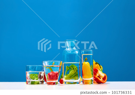 Still life with broccoli, red and yellow pepper on table with bottle of water on blue studio background. Bright colors. Fruit detox Still life with broccoli, red and yellow pepper on table with bottle of water on blue studio background. Bright colors. Fruit detox 101736331