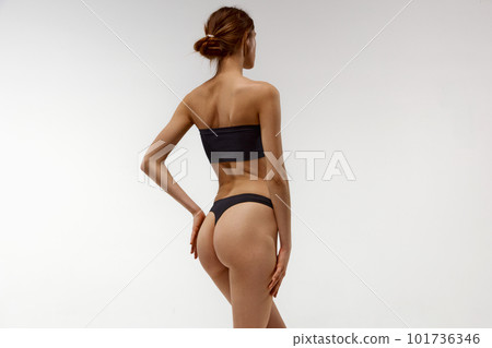 Young girl, model with slim, sportive, fit body, buttocks posing in underwear against white studio background. Anti-cellulite care Young girl, model with slim, sportive, fit body, buttocks posing in underwear against white studio background. Anti-cellulite care 101736346