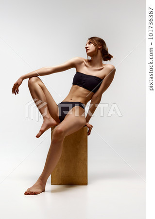 Portrait of beautiful young girl posing in black underwear against white studio background. Slim, fit, relief body shape 101736367