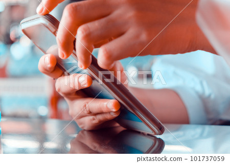 Close up of female hands using mobile smart phone in a cafe. Close up of female hands using mobile smart phone in a cafe. 101737059