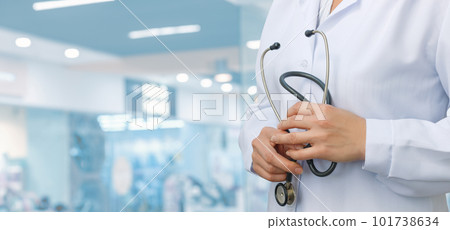 The doctor is standing and holding a stethoscope . 101738634