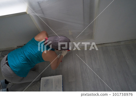 Woman paints the wall with a roller 101738976