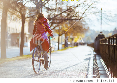 modern woman in red rain coat outdoors in city riding bicycle modern woman in red rain coat outdoors in city riding bicycle 101739151