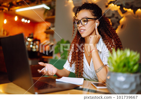 Portrait of African American woman sitting at cafe having video call on laptop computer. Portrait of African American woman sitting at cafe having video call on laptop computer. 101739667