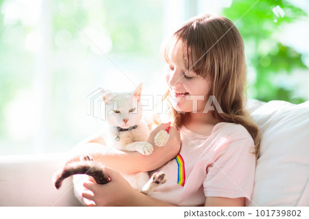 Child playing with kitten. Cat and kid at home. 101739802