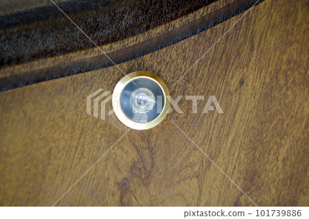 Close up eye hole on wood. close up, door lens peephole on white wooden texture. Door eye, at the door. Out of focus 101739886