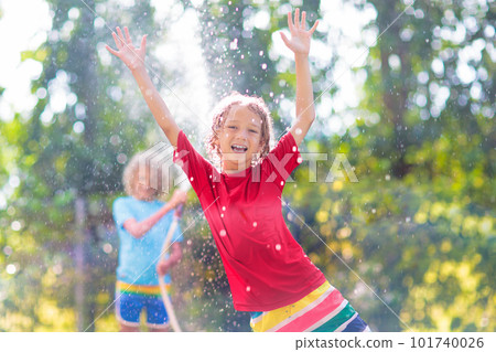 Kids play with water sprinkle hose. Summer garden Kids play with water sprinkle hose. Summer garden 101740026