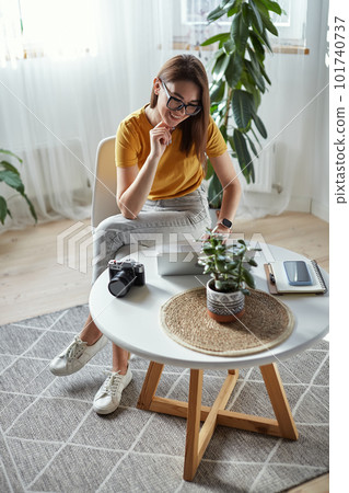 Young woman photographer working at home using computer sitting at table at home Young woman photographer working at home using computer sitting at table at home 101740737