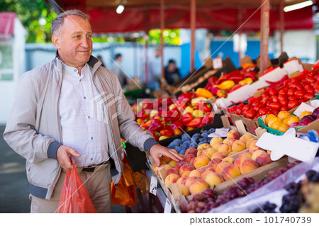 Man choosing peaches in market Man choosing peaches in market 101740739