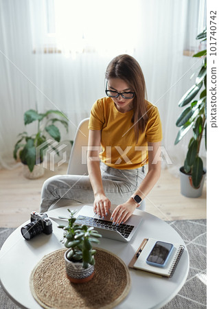 Young woman photographer working at home using computer sitting at table at home Young woman photographer working at home using computer sitting at table at home 101740742