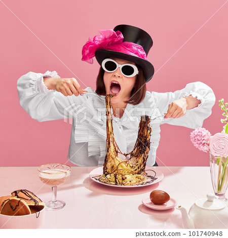 Passionate eater. Emotinal woman in cylinder hat and suglasses eating spaghetti with chocolate sauce against pink background. Passionate eater. Emotinal woman in cylinder hat and suglasses eating spaghetti with chocolate sauce against pink background. 101740948