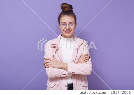 Indoor portrait of magnetic positive beautiful cute model with bun crossing her arms, wearing accessories, looking directly at camera, being in good mood, wearing stylish clothes. Youth concept. Indoor portrait of magnetic positive beautiful cute model with bun crossing her arms, wearing accessories, looking directly at camera, being in good mood, wearing stylish clothes. Youth concept. 101742066