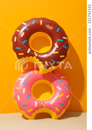 Rubber rings on sand against orange background Rubber rings on sand against orange background 101742342