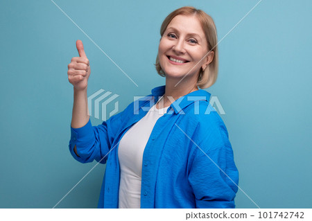 smiling mature woman showing class like on blue background with copyspace 101742742