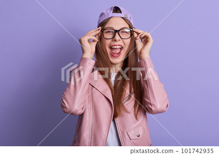 Horizontal studio portrait of sincere energetic lovely long haired teenager wearing eyeglasses, opening mouth widely, looking directly at camera, wearing casual clothes. Youth and fashion concept. Horizontal studio portrait of sincere energetic lovely long haired teenager wearing eyeglasses, opening mouth widely, looking directly at camera, wearing casual clothes. Youth and fashion concept. 101742935