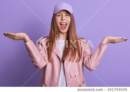 Image of happy student girl posing with spreading hands and yelling something, woman wearing casual attire and cap, has positive emotions, expresses joy and happiness. People emotions concept. Image of happy student girl posing with spreading hands and yelling something, woman wearing casual attire and cap, has positive emotions, expresses joy and happiness. People emotions concept. 101743039