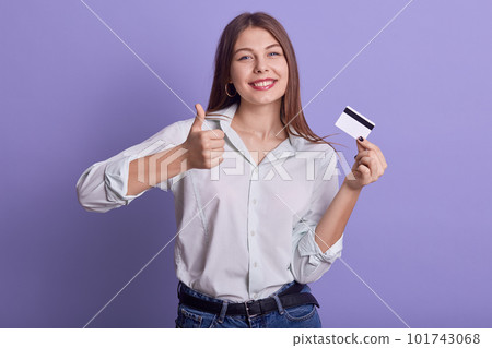 Image of cheerful positive charismatic youngster doing credit payments, making gesture, showing sign of approval super, holding credit card, wearing casual clothes, having tender smile. Money concept. 101743068