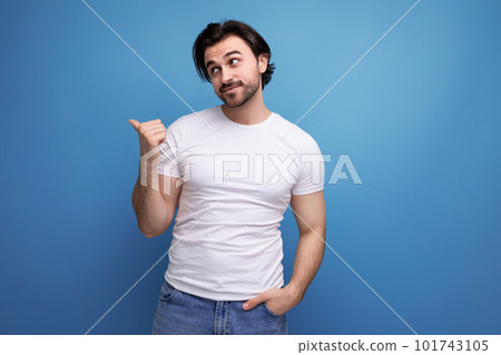 young man in a white t-shirt points his finger to the side on a studio background with copyspace young man in a white t-shirt points his finger to the side on a studio background with copyspace 101743105