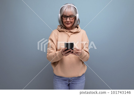 stylish 60s granny with gray hair learns again and listens to music with headphones on studio stylish 60s granny with gray hair learns again and listens to music with headphones on studio 101743146