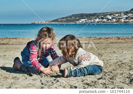 A couple of cute white Caucasian kids playing on a sandy beach in the winter A couple of cute white Caucasian kids playing on a sandy beach in the winter 101744110