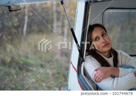 Portrait of a caucasian woman looking out of a trailer window. Travel in a camper in autumn. Portrait of a caucasian woman looking out of a trailer window. Travel in a camper in autumn. 101744678