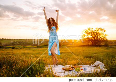 Young woman sits on a plaid with a book. Summer picnic in nature. Healthy food. 101744840