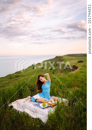 Young woman sits on a plaid with a book. Summer picnic in nature. Healthy food. Young woman sits on a plaid with a book. Summer picnic in nature. Healthy food. 101744851