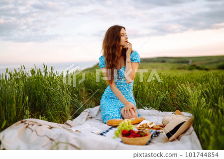 Young woman sits on a plaid with a book. Summer picnic in nature. Healthy food. Young woman sits on a plaid with a book. Summer picnic in nature. Healthy food. 101744854