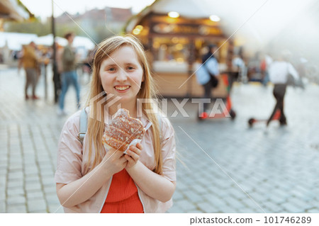 smiling girl in jacket at fair in city eating trdelnik 101746289