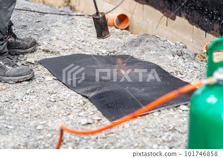 installation of protective waterproofing on the foundation and walls of the building. warmed by an open fire 101746858