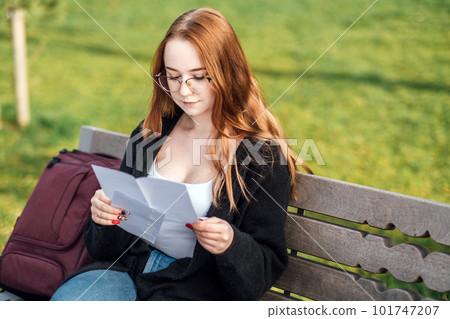 Understanding Student Loan Repayment Options. Pros and Cons of Federal vs Private Student Loans. Young student girl in glasses and with laptop and books reading letter outdoors 101747207