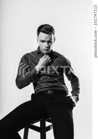 A stylish black and white portrait of a man in a shirt posing on a white cyclorama. 101747215