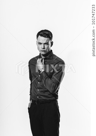 A stylish black and white portrait of a man in a shirt posing on a white cyclorama. 101747233