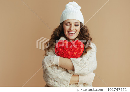 happy woman in beige sweater, mittens and hat against beige happy woman in beige sweater, mittens and hat against beige 101747351