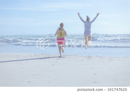 stylish mother and teenage daughter at beach running 101747620