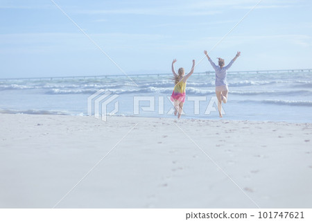 Seen from behind mother and child at beach rejoicing and running 101747621