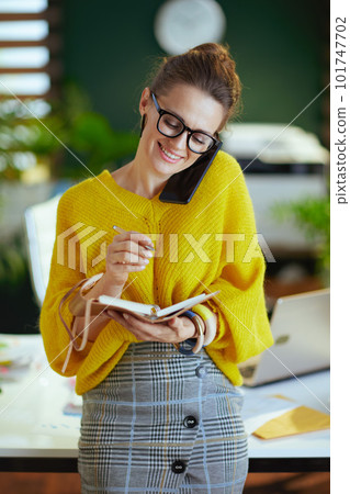 happy business owner woman in green office talking on phone 101747702