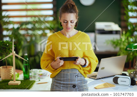 business owner woman in sweater in green office using phone 101747703