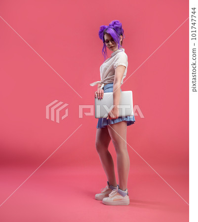 sexy girl with glasses with purple hair with a laptop in summer clothes on a pink background copy paste 101747744