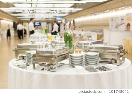 Waiters prepare buffet before a coffee break at business conference meeting. Focus on plates and dishes on the table. 101748041
