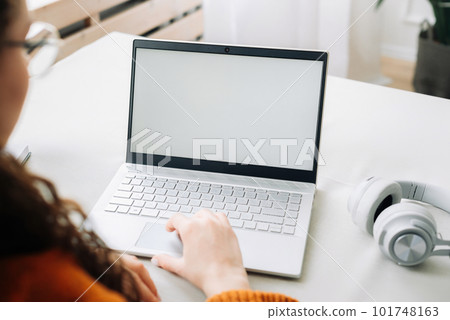Over shoulder view of woman student elearning looking at white mock up blank screen using laptop Over shoulder view of woman student elearning looking at white mock up blank screen using laptop 101748163