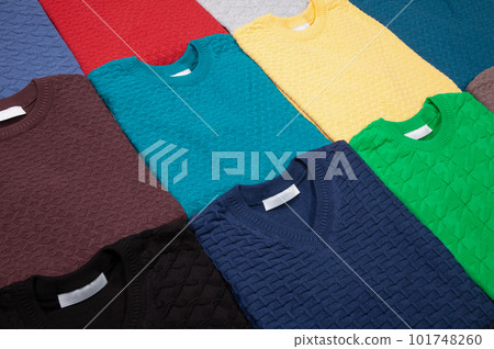 Collection of knitted jumpers of various colours folded 101748260
