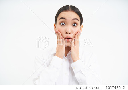 Portrait of young woman entrepreneur, manager looks surprised, touches her cheeks with shocked face expression, stands isolated on white background 101748642