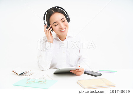 People and workplace. Smiling asian woman sits in office, student listening music in headphones and holding digital tablet, white background 101748659