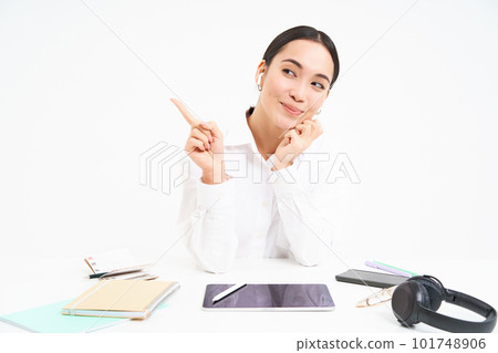 Portrait of asian businesswoman sits in office with tablet, points left and smiles, shows advertisement, office banner, white background Portrait of asian businesswoman sits in office with tablet, points left and smiles, shows advertisement, office banner, white background 101748906
