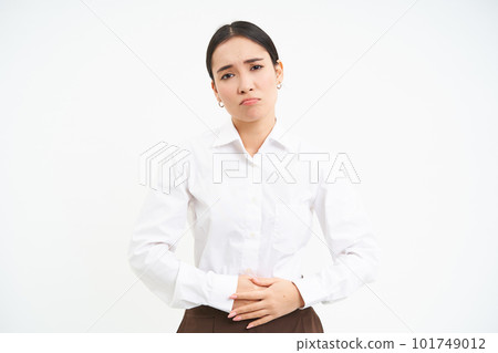 Image of asian office lady touches her belly, looks upset from discomfort in stomach, suffers period cramps at work, white background Image of asian office lady touches her belly, looks upset from discomfort in stomach, suffers period cramps at work, white background 101749012